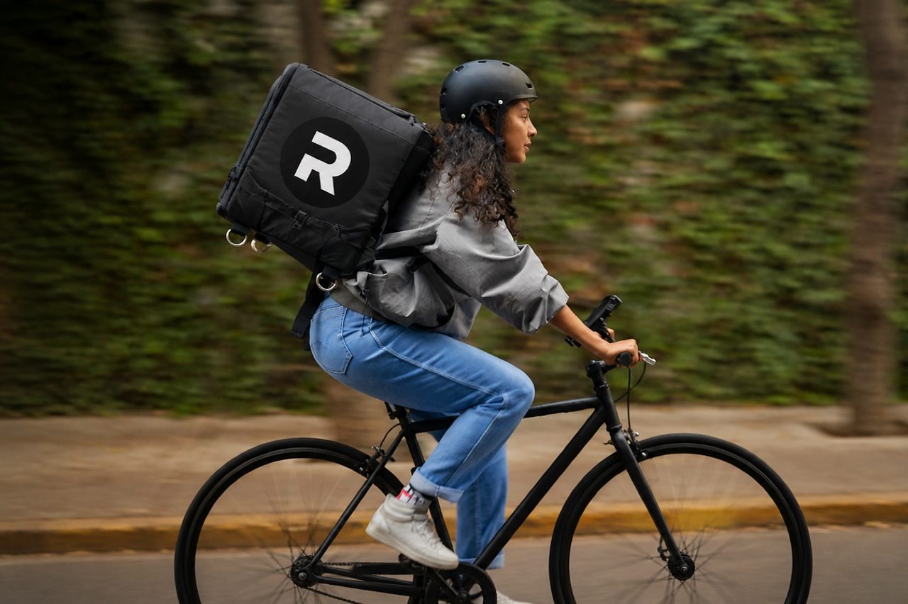 Courier on a bicycle wearing a black Ryde delivery backpack
