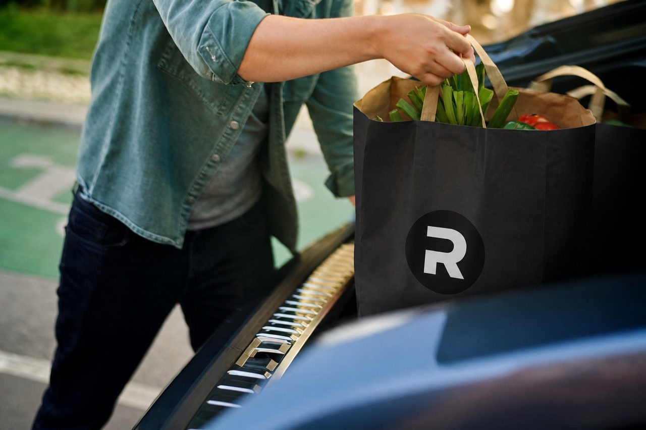 Loading a black Ryde grocery bag into a car trunk